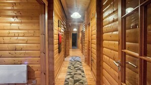 A wooden hallway with a geometric patterned rug, wooden walls, and a ceiling light fixture. - 4 bedroom accommodation in Kenwick, near Louth (Kenwick, near Louth)
