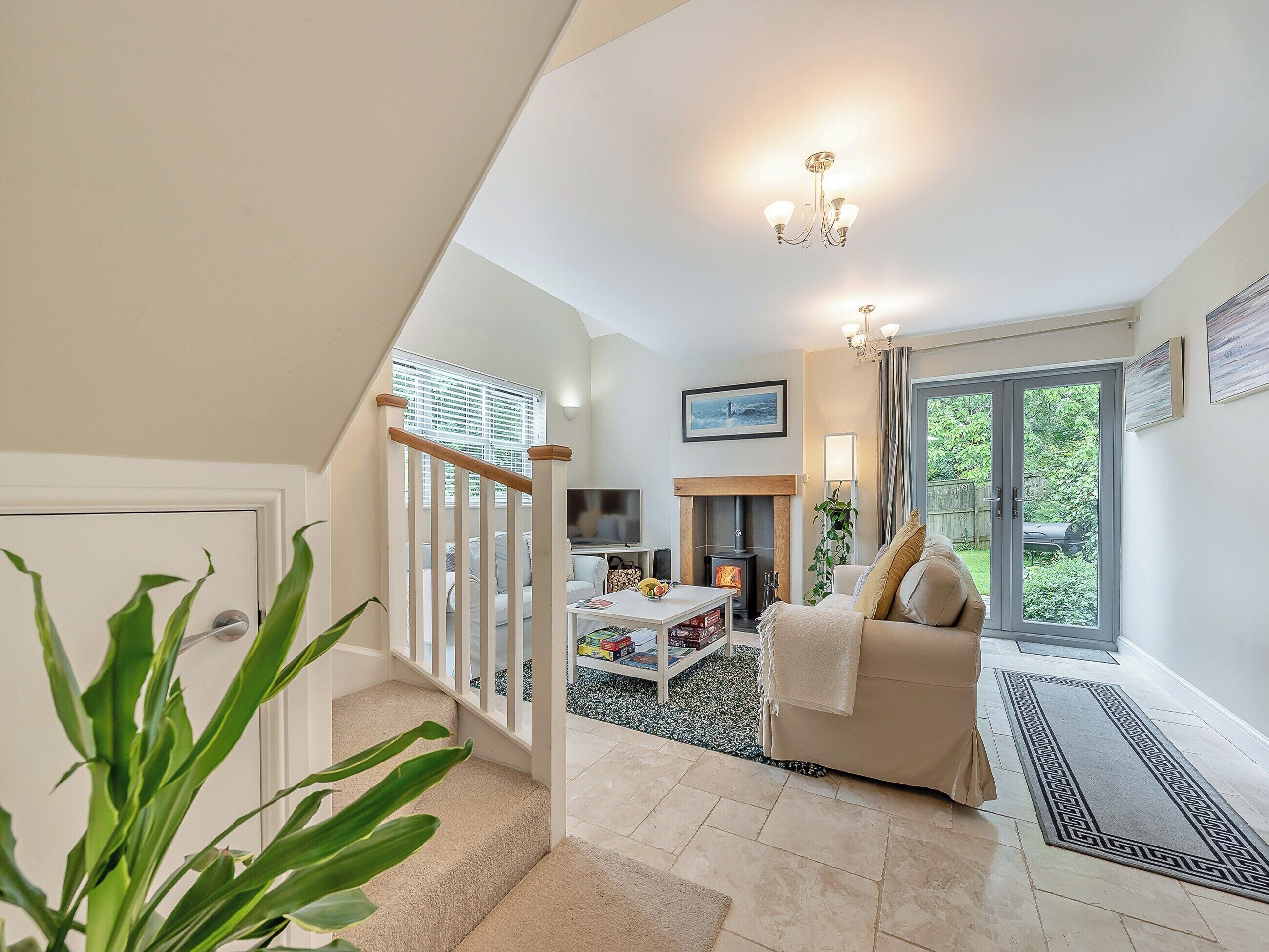 A modern living room with a fireplace, a sofa, a coffee table, and a staircase leading to another level.