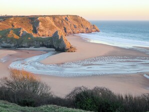 Eine Küstenlandschaft mit Sandstrand, Felsen und ruhigem Meer.