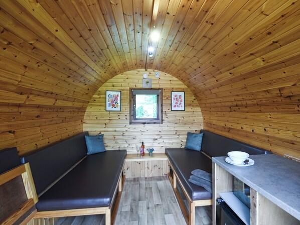 Een houten interieur met bogen, twee zithoeken, een kleine tafel en een raam.