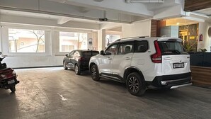 A spacious indoor parking area with a white SUV and a motorcycle. - HOTEL FALLS STREET BY DC HILLS (Rishikesh)