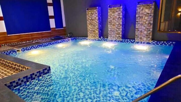 A swimming pool with blue mosaic tiles, stone pillars, and a checkered floor pattern. - HOTEL FALLS STREET BY DC HILLS (Rishikesh)