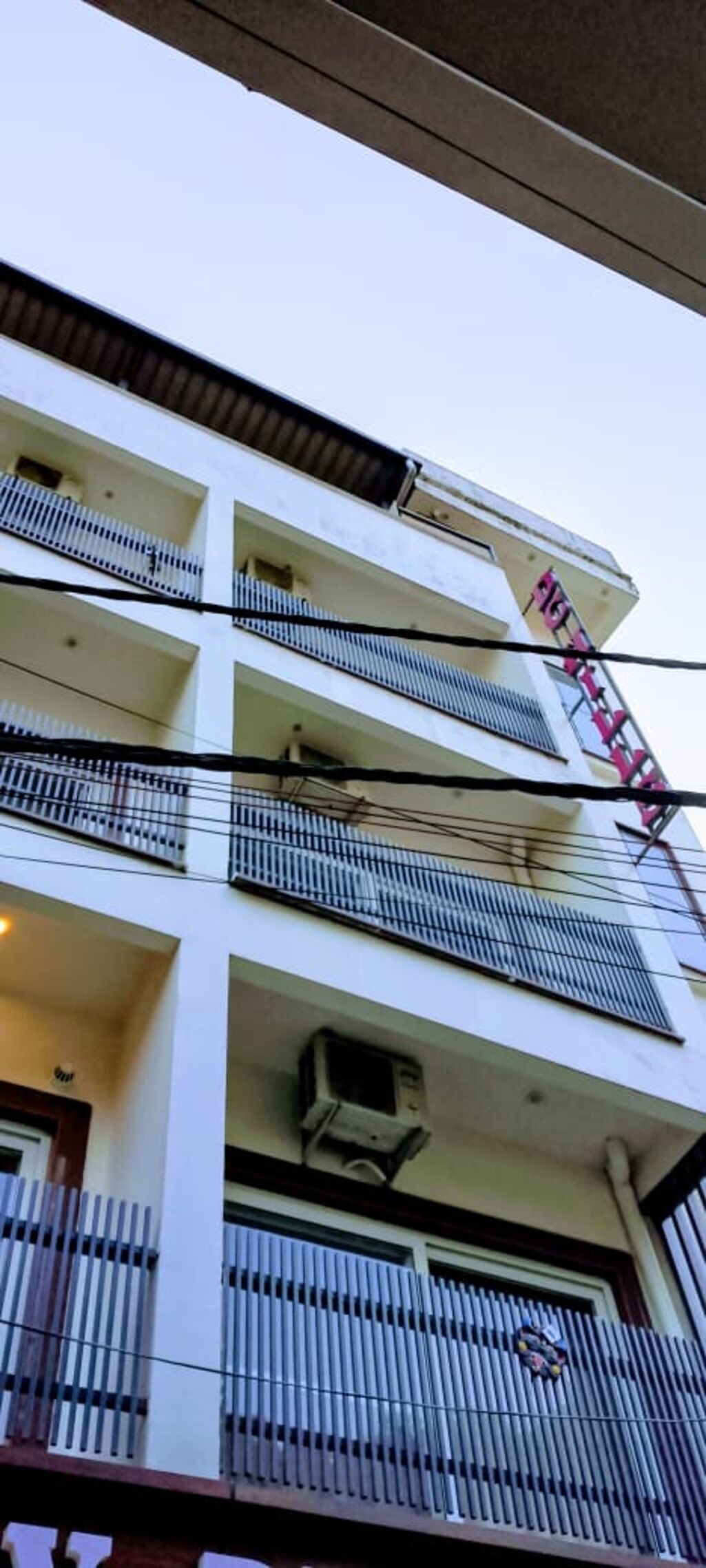 Un edificio de varios pisos con balcones y unidades de aire acondicionado.
