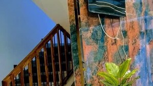 A staircase with wooden railings leading to a landing with a marble wall and a flat-screen TV mounted on it. - HOTEL FALLS STREET BY DC HILLS (Rishikesh)