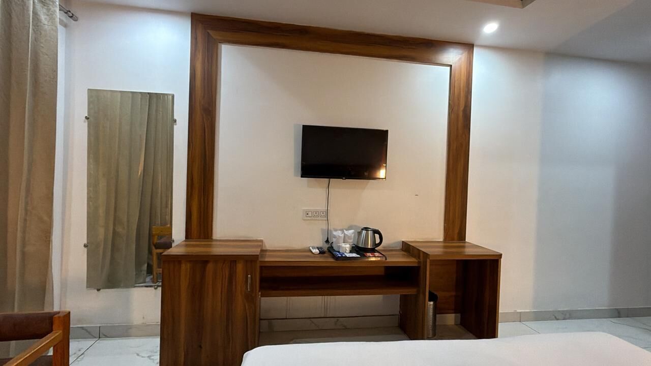 Ein Hotelzimmer mit Bett, Holztisch, Fernseher und einem kleinen Tisch mit Wasserkocher und Tassen.
