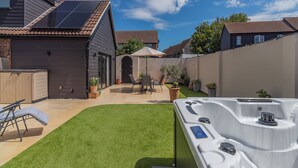 Une maison moderne dotée de panneaux solaires, d’un jacuzzi et d’une pelouse bien entretenue.