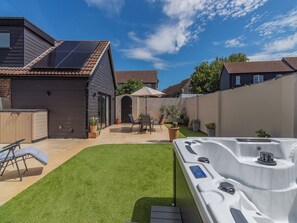 Une maison moderne dotée de panneaux solaires, d’un jacuzzi et d’une pelouse bien entretenue.