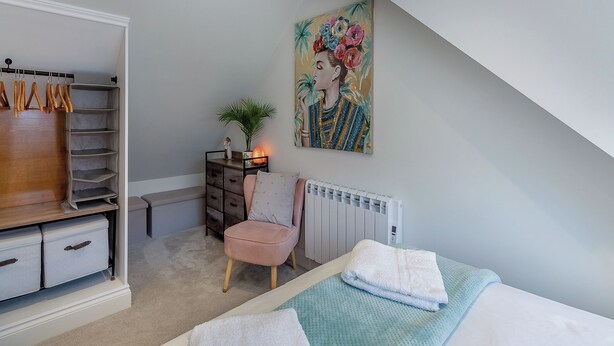 A bedroom with a bed, a chair, a radiator, a wardrobe, and a painting on the wall. - Olive Breeze is a bright spacious property in the old part of Felixstowe. (Felixstowe)