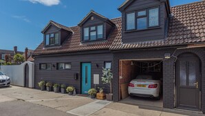 Une maison à deux étages avec un garage, une porte bleue et une voiture garée à l’intérieur.