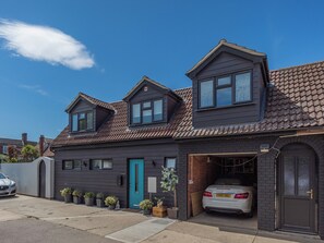 A two-story house with a garage, a blue door, and a car parked inside.