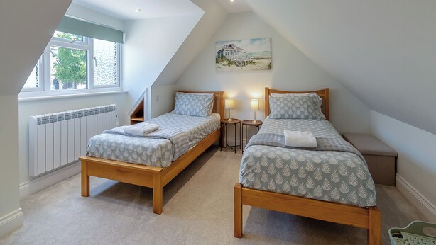 Une chambre avec deux lits simples, une fenêtre, un radiateur et un tableau au mur.