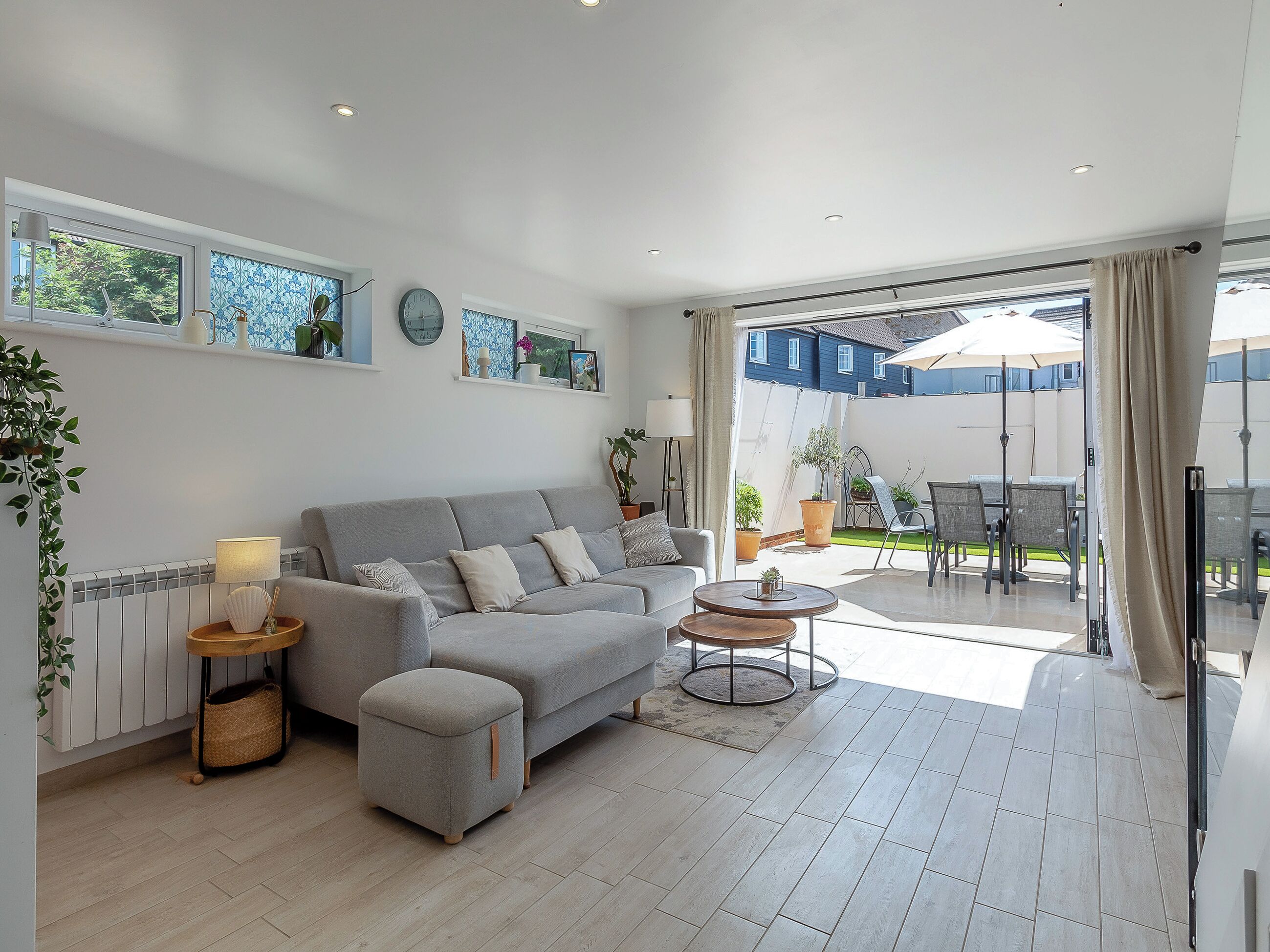Un soggiorno moderno con un divano grigio, un tavolino rotondo e vista su una zona patio esterna.