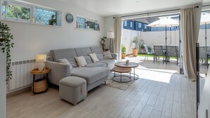 A modern living room with a grey sofa, a round coffee table, and a view of an outdoor patio area. - Olive Breeze is a bright spacious property in the old part of Felixstowe. (Felixstowe)