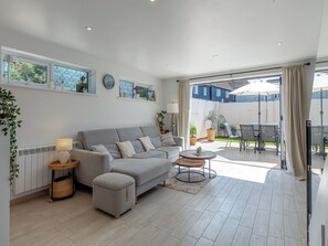 Un salón moderno con un sofá gris, una mesa de centro redonda y vistas a un patio exterior.