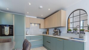 Une cuisine moderne avec des meubles de couleur bleu clair, une machine à expresso en acier inoxydable et une fenêtre donnant sur un beau paysage.
