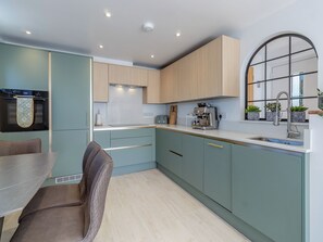 Une cuisine moderne avec des meubles de couleur bleu clair, une machine à expresso en acier inoxydable et une fenêtre donnant sur un beau paysage.