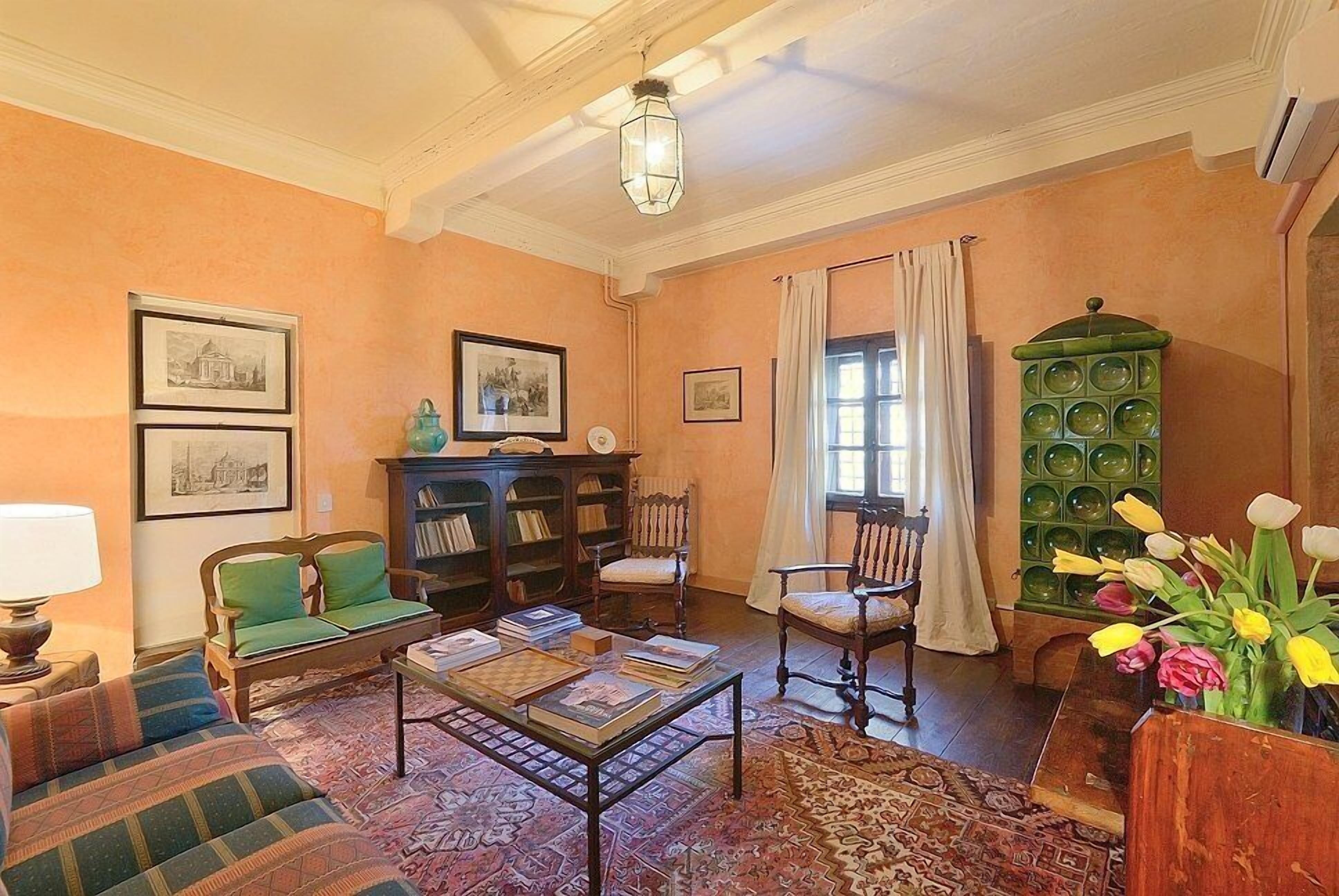 A cozy living room with a sofa, armchairs, a coffee table, a bookshelf, and a green cabinet.