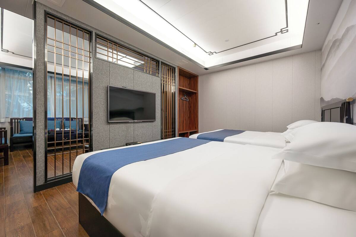Une chambre d’hôtel avec deux lits, un téléviseur fixé au mur et une porte coulissante donnant sur un balcon.