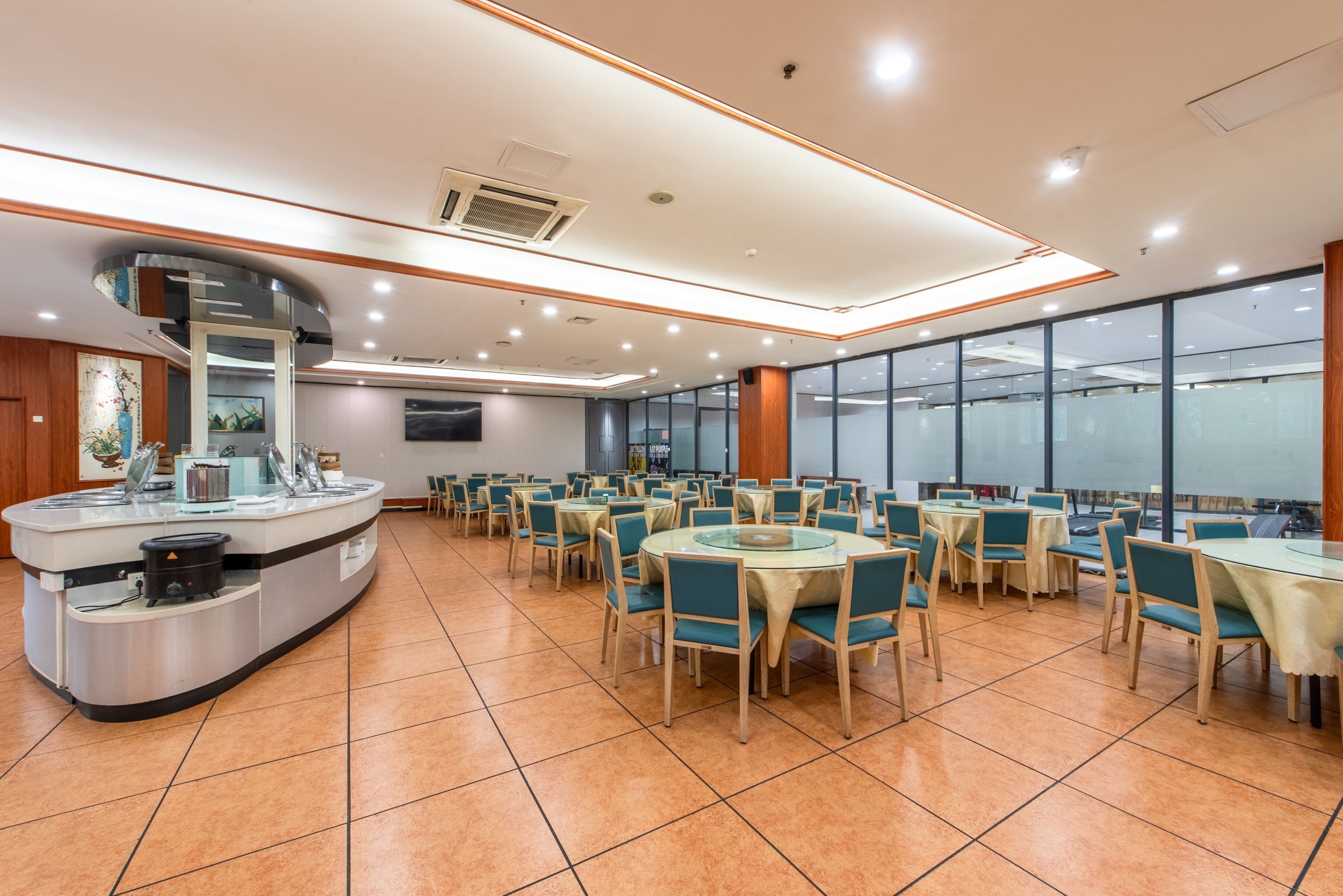 Un restaurante espacioso con mesas y sillas redondas, una barra central y grandes ventanales que ofrecen vistas.