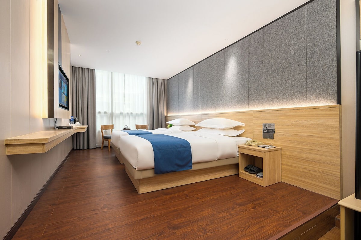 Une chambre d’hôtel moderne avec un grand lit, des tables de chevet, une télévision et un plancher en bois.