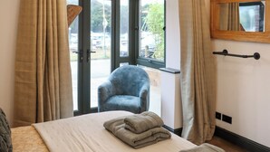 Ett hotellrum med en säng, en stol och ett fönster med utsikt över omgivningen.