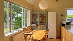 A kitchen with a dining table, chairs, a refrigerator, a microwave, and a cabinet with glass doors. - 3 bedroom accommodation in Lochranza (Lochranza)