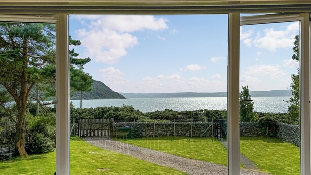A room with a large window overlooking a grassy yard and a body of water. - 3 bedroom accommodation in Lochranza (Lochranza)