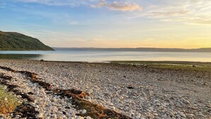 A pebbled beach with a calm sea and distant hills. - 3 bedroom accommodation in Lochranza (Lochranza)