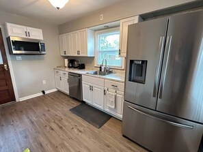 A modern kitchen with white cabinets, stainless steel appliances, and a window providing natural light. - Chic Central Retreat (Evansville)