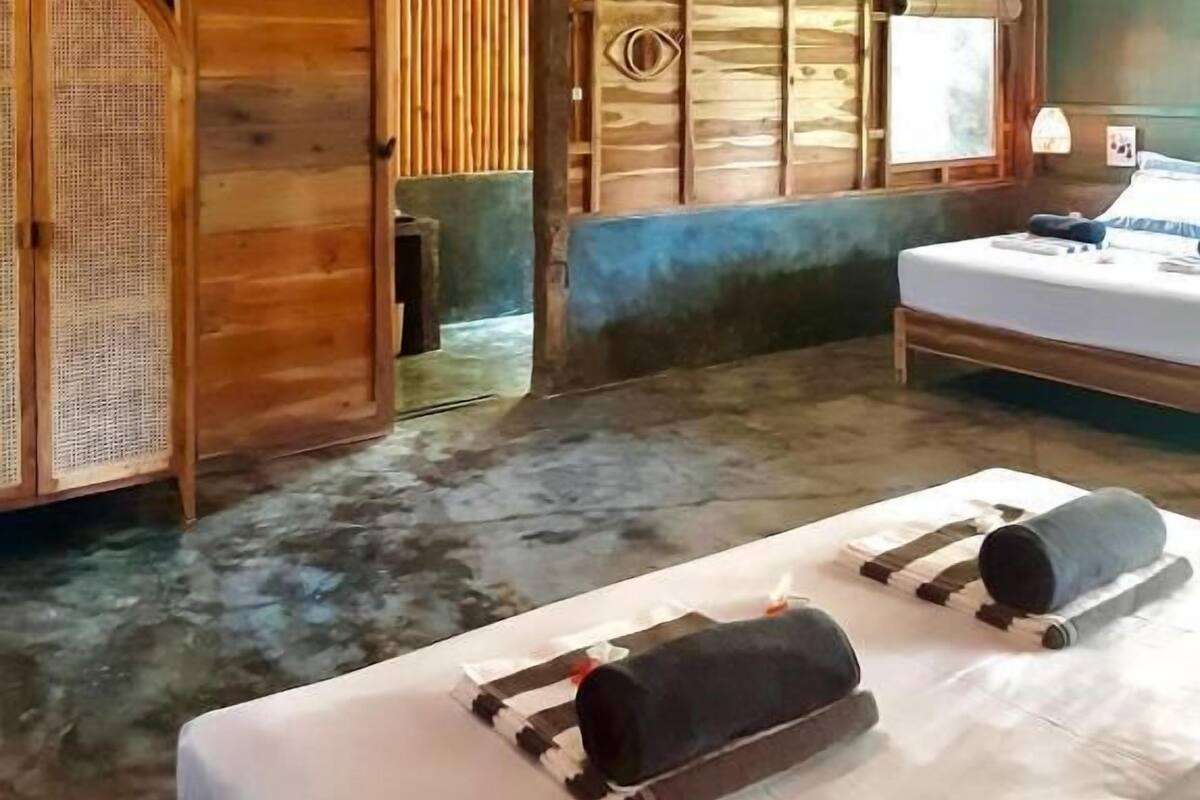 Une pièce rustique en bois, avec un lit, une table et deux lampes suspendues.