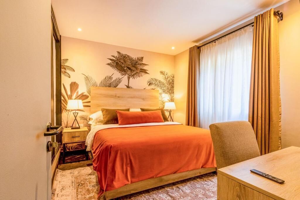 A hotel room with a bed, a chair, a nightstand, and a lamp.