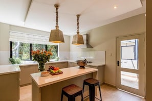 A modern kitchen with a central island, pendant lighting, and a view of the outdoors. - Macadamia Boutique Living (Nairobi)