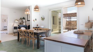 Una cocina moderna con una isla central, sillas de madera y lámparas colgantes de mimbre.