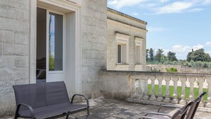 Un edificio de piedra con balcón, asientos al aire libre y vistas del paisaje circundante.