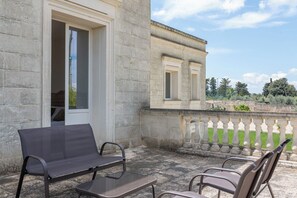 A stone building with a balcony, outdoor seating, and a view of the surrounding landscape. - Villa in Lizzanello with 5 bedrooms sleeps 10 (Lizzanello)