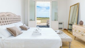 Un dormitorio con una cama grande, un banco, un aparador y un espejo.