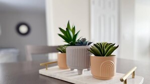 A marble tray with three potted plants and a gold-colored tray stand on a wooden table.