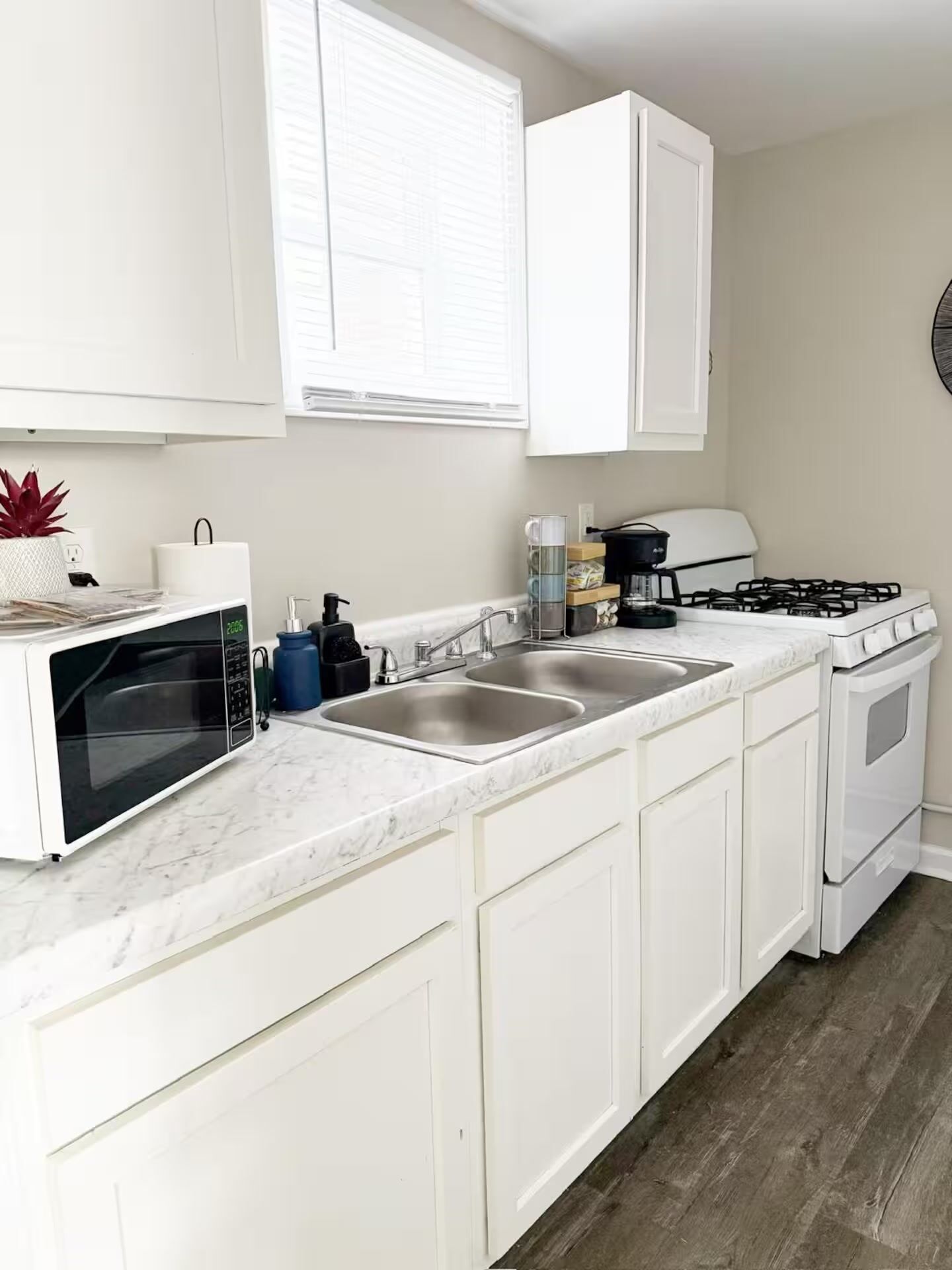 A kitchen with white cabinets, a microwave, a stove, and a sink.