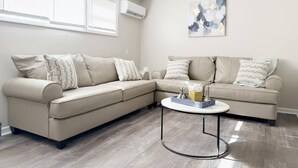 A modern living room with a beige sectional sofa, a round coffee table, and a painting on the wall.