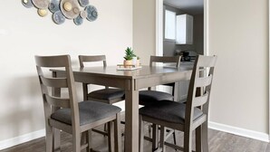 A dining area with a round table, six chairs, and a decorative wall piece.