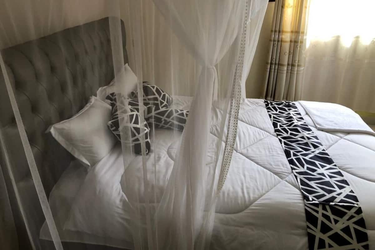 A bed with a canopy, pillows, and a patterned bedspread.