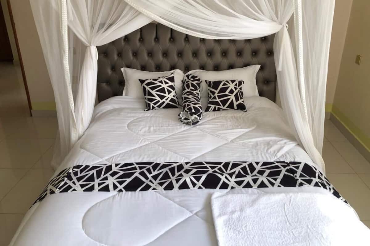 A bed with a tufted headboard, white bedding, and geometric-patterned pillows.