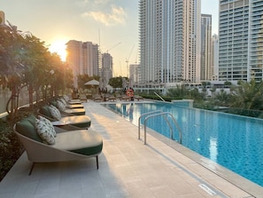 A poolside area with lounge chairs and a swimming pool, surrounded by high-rise buildings. - FIRST CLASS | 1BR | Vida Creek Beach Bliss (Dubai Creek Harbour)
