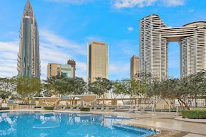 A modern hotel with a pool, surrounded by trees and featuring a view of tall buildings. - FIRST CLASS | 2BR | High-Floor Sky Views (Downtown)