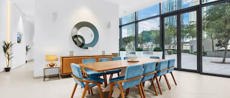 Una sala de conferencias moderna con una mesa de madera y sillas azules, ventanas amplias con vista a la ciudad y un adorno circular en la pared.