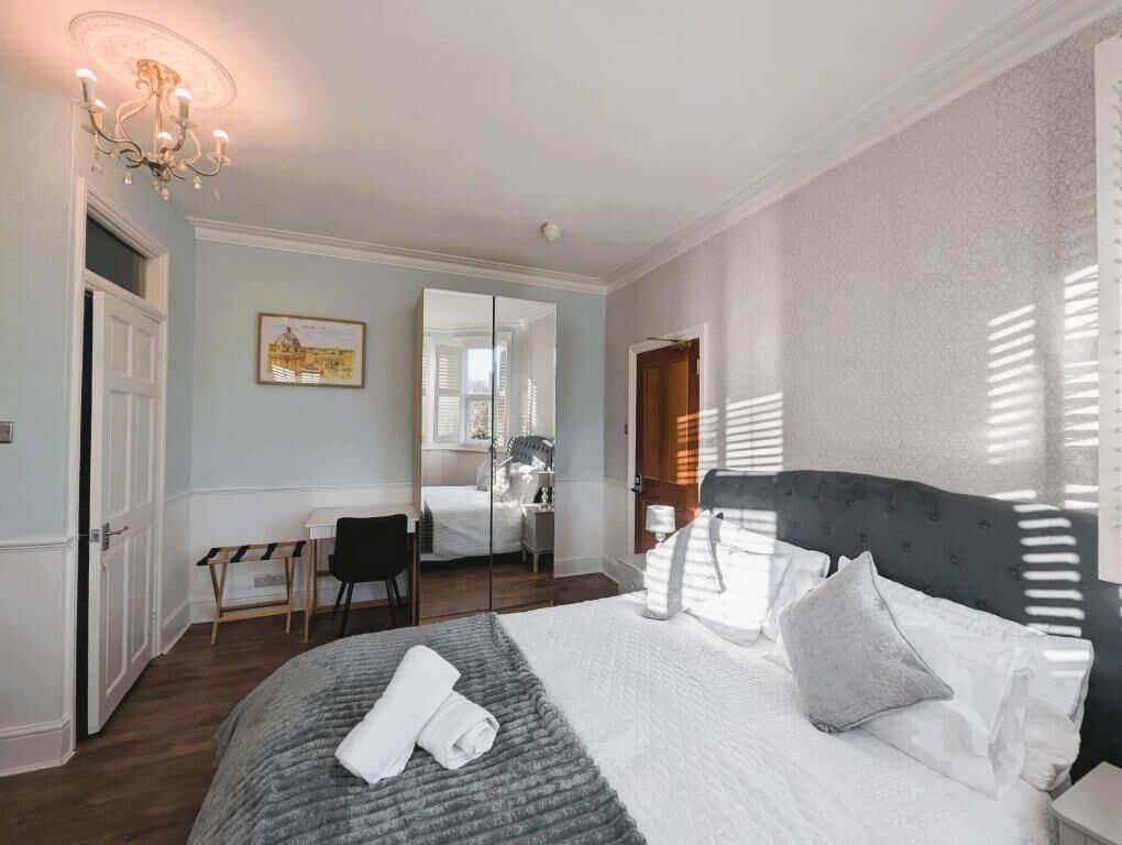 A bedroom with a large bed, a desk, and a chair.