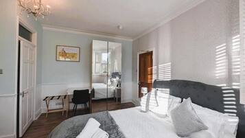 A bedroom with a large bed, a desk, and a chair.