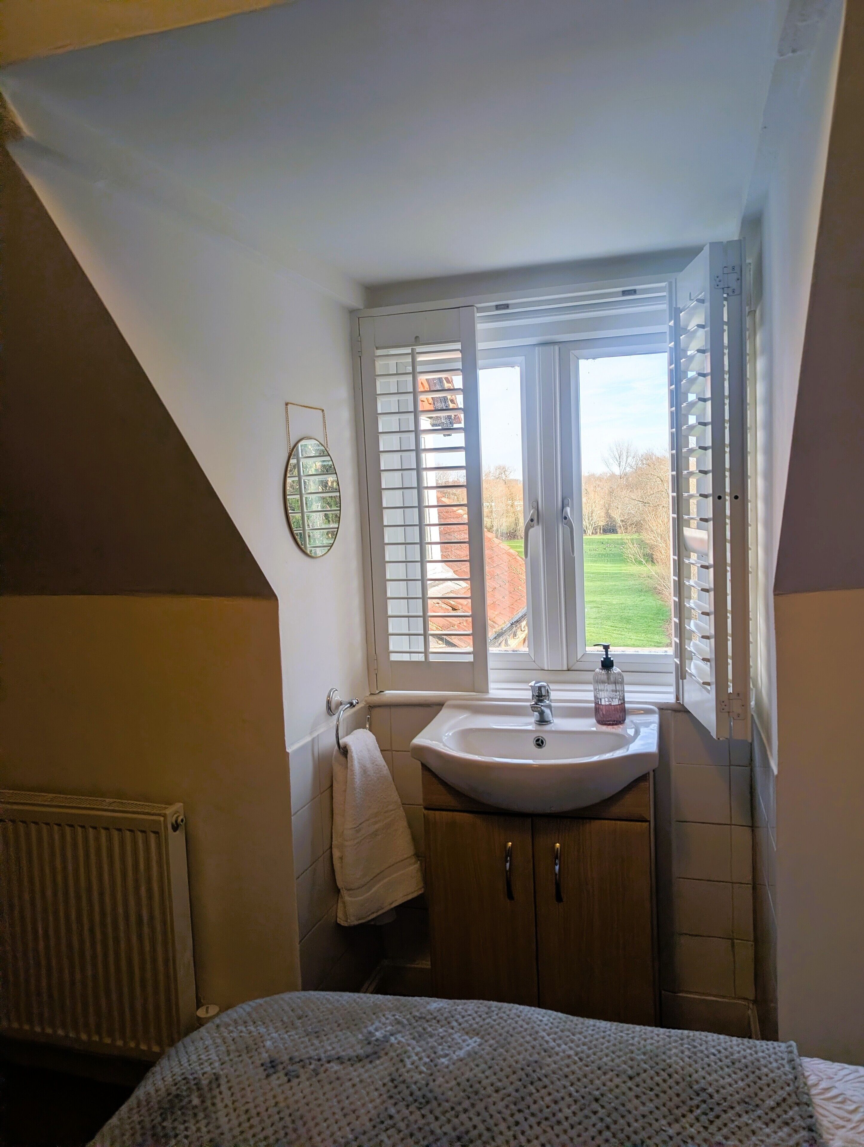 Une chambre avec une grande fenêtre, une table de chevet et un radiateur.