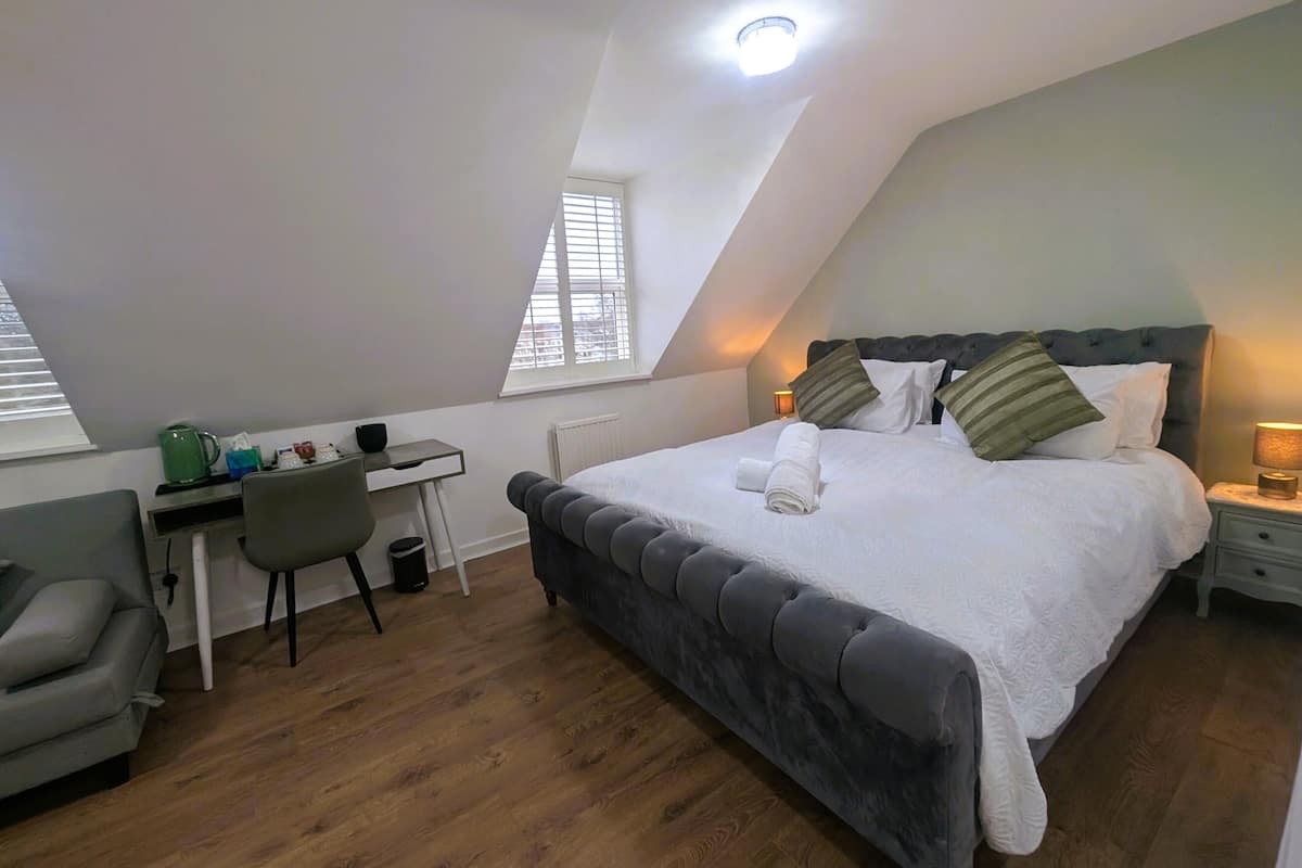 A bedroom with a bed, a desk, and a chair.