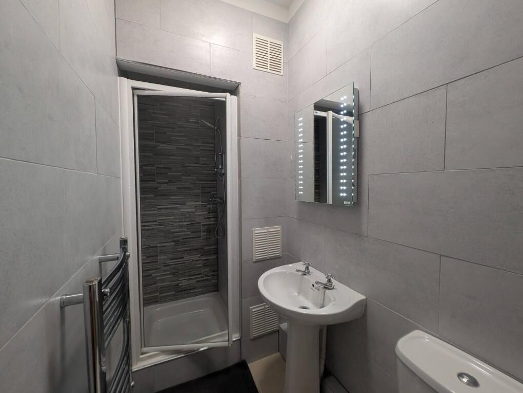 A modern bathroom with a shower, a sink, and a toilet.